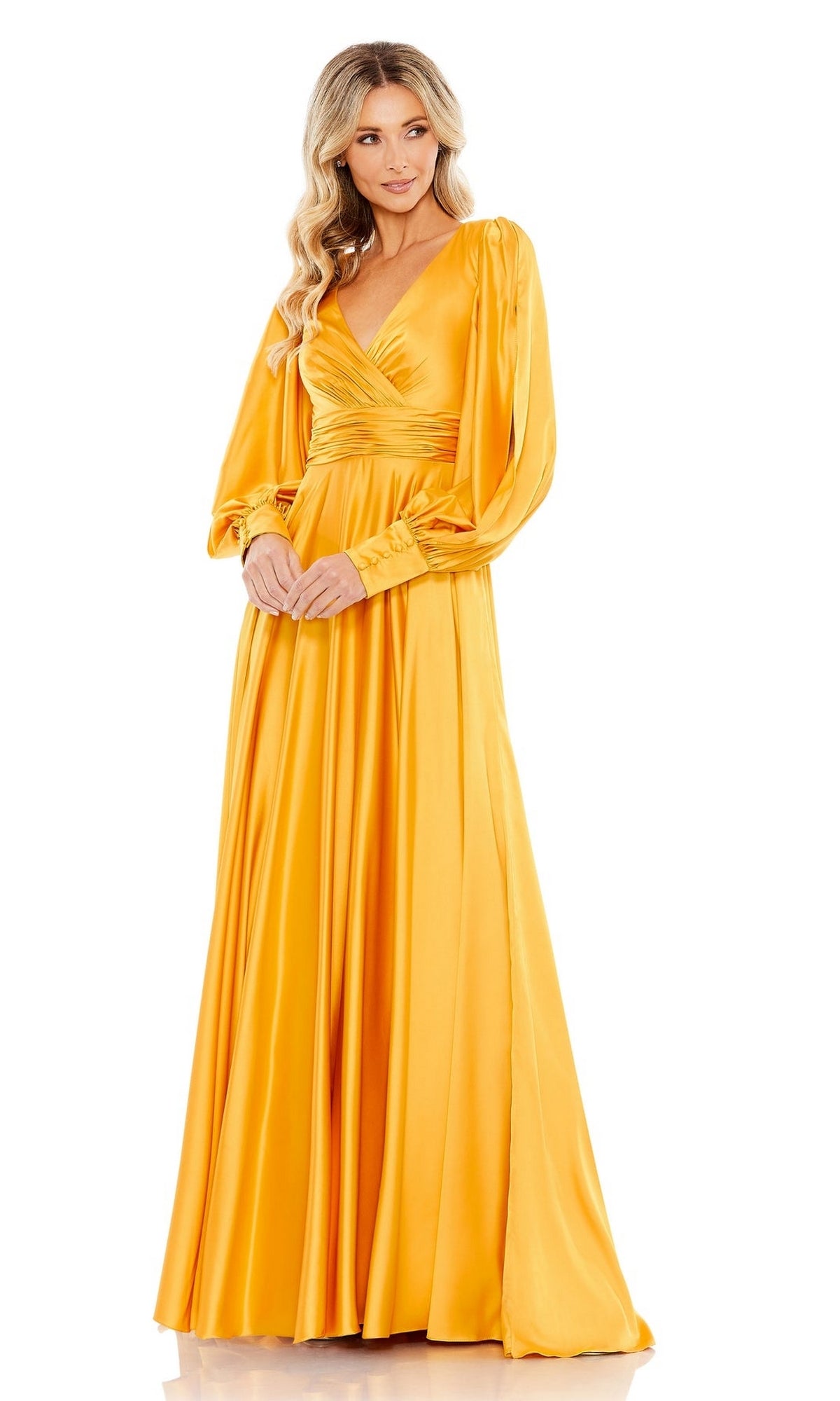 A woman stands against a white background wearing the Long Formal Dress 67847 by Mac Duggal—a golden yellow gown featuring long sleeves, a V-neckline, and a flowing silhouette.